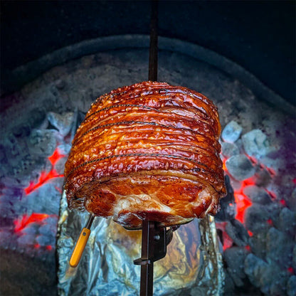 Rotisserie pork over a bed of coals, using the Combustion Predictive Thermometer to measure temperature.